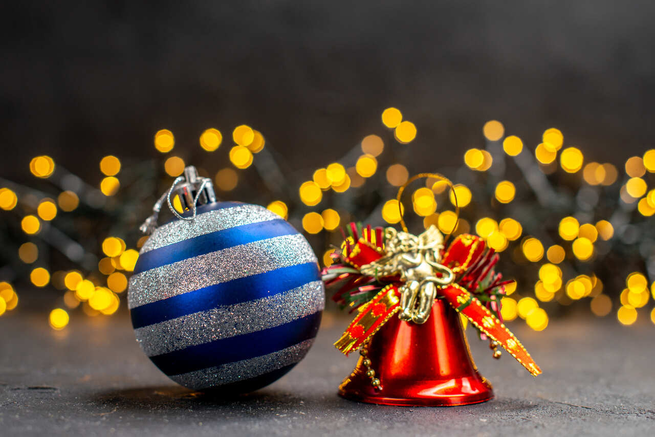 Blue ornament and red bell with festive string lights