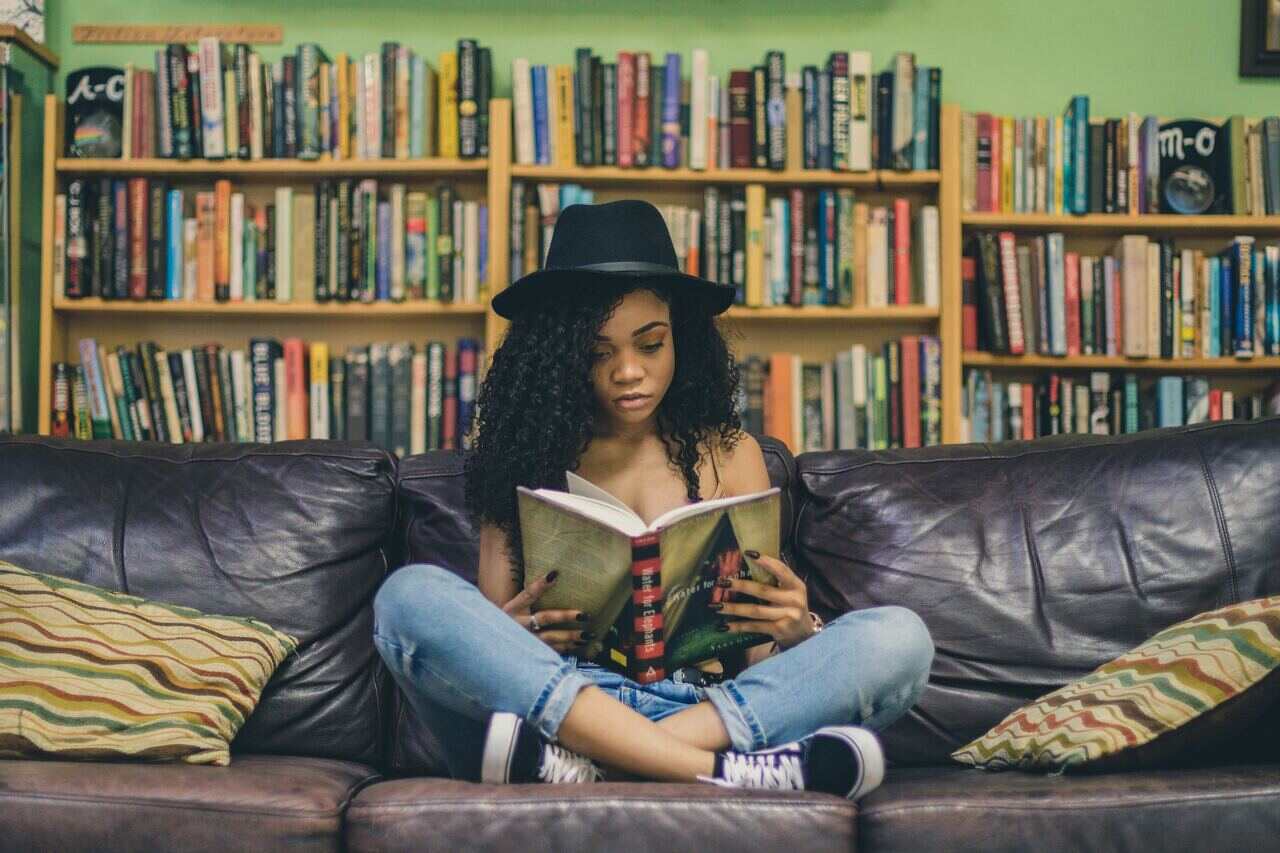 A woman reading a book on a couch in a library