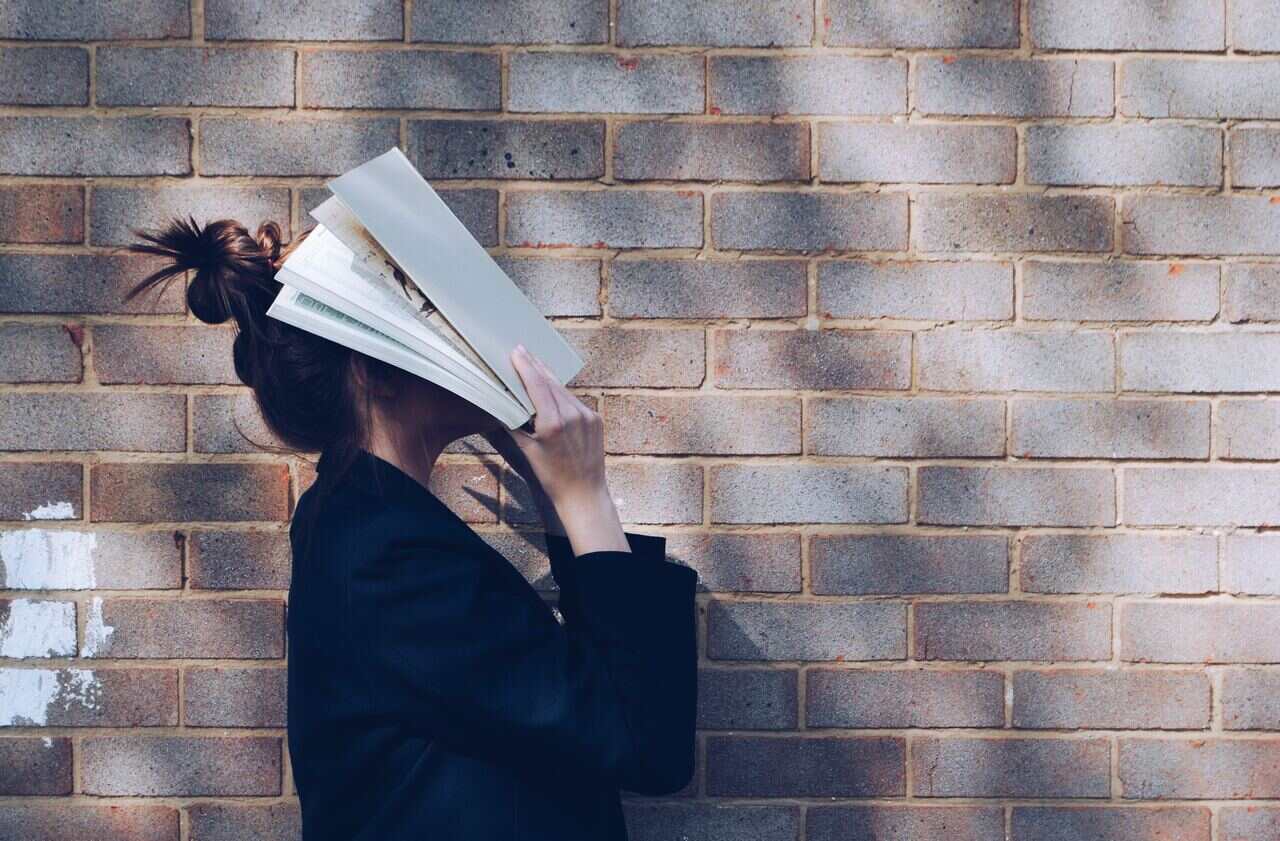 Person holding a book in front of their face