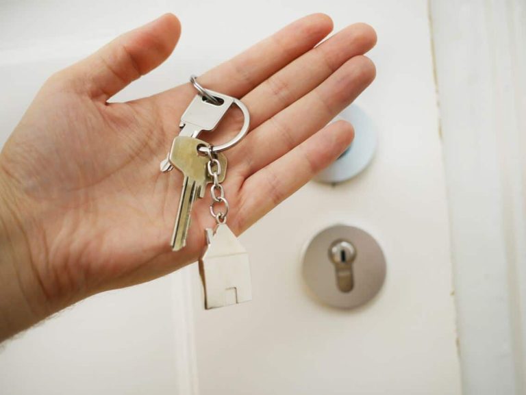 Hand holding a house key in front of a door