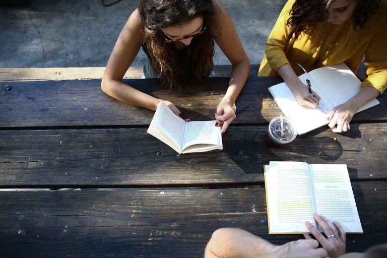 Group of students reading and studying at a wooden table