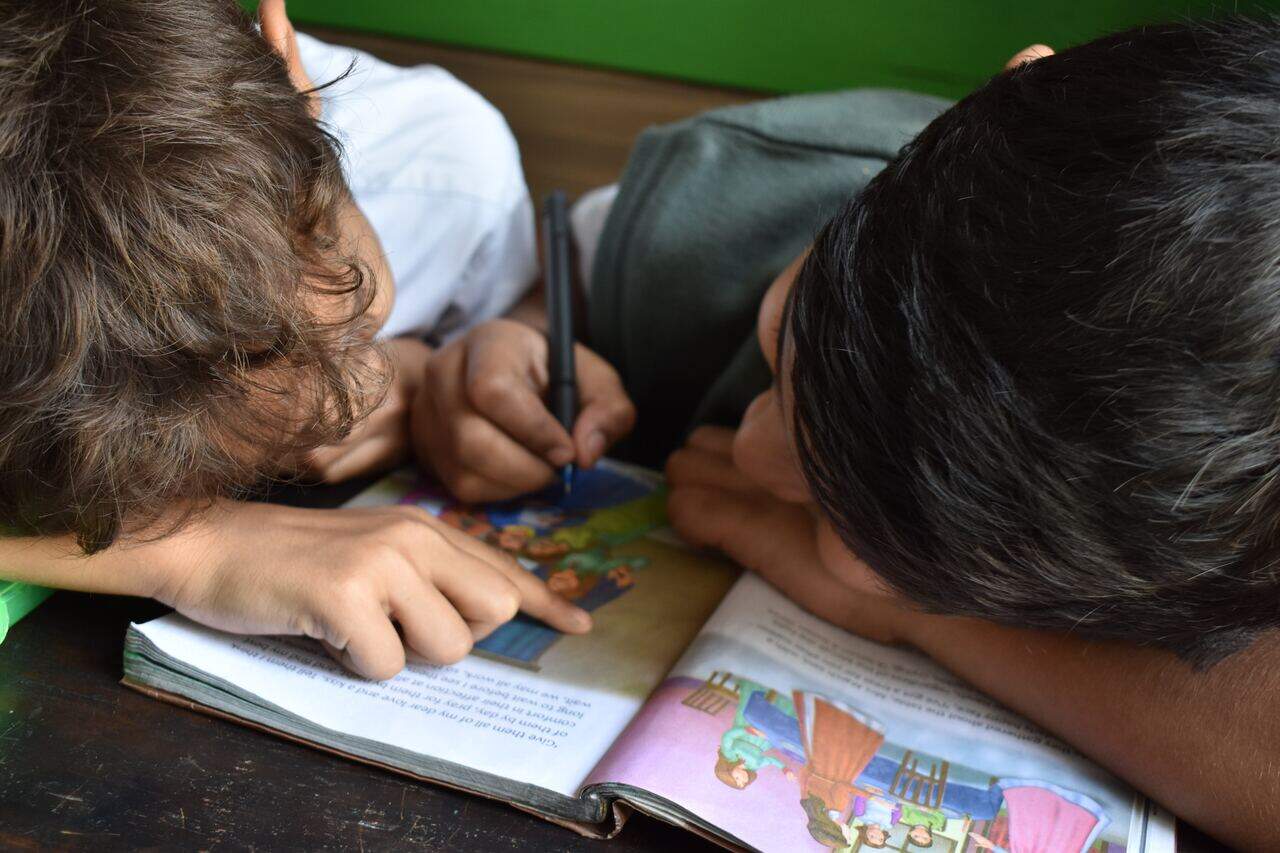 Two boys focused on reading and writing in a book