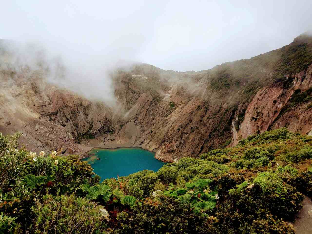 Volcanic crater lake surrounded by mist and greenery