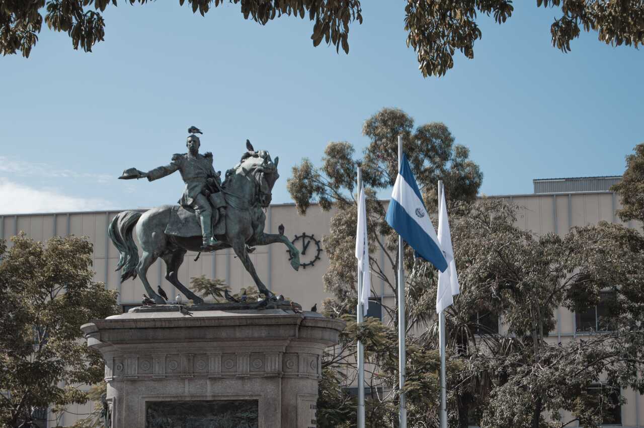 Equestrian statue with flags under a clear sky