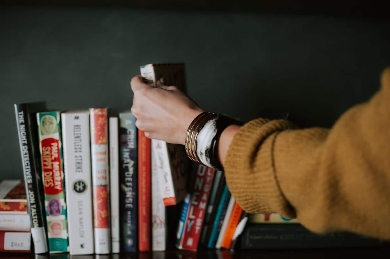 Hand reaching for a book on a shelf