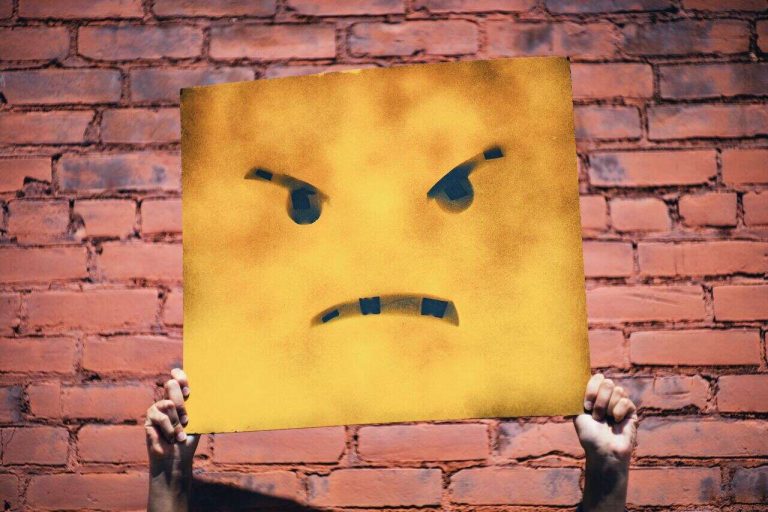 Person holding a yellow angry face sign