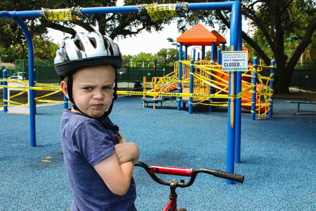 Child with bike pouting at closed playground