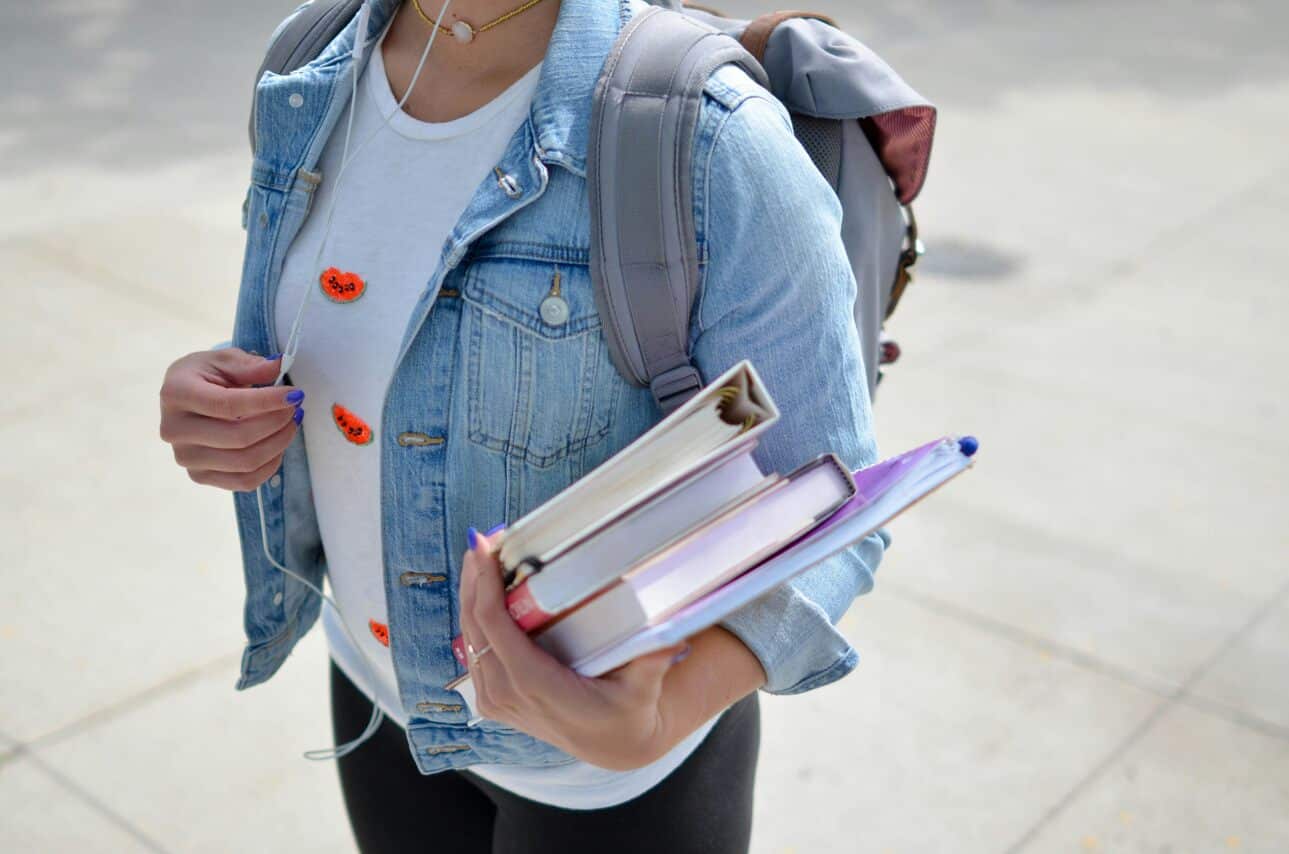 Student with backpack holding books and notebooks