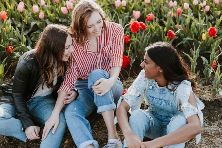 Three friends sitting together in a flower garden