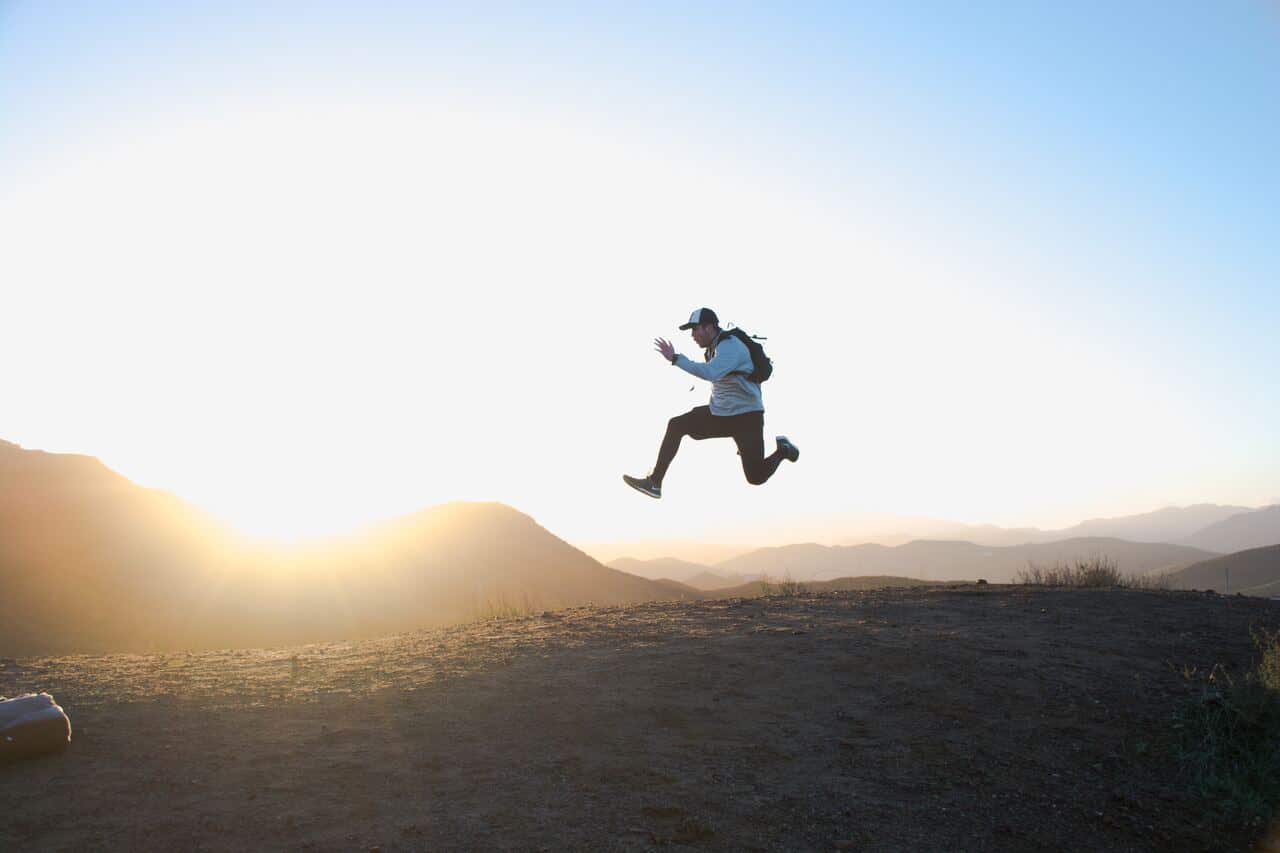 Person leaping mid-air during a mountain hike