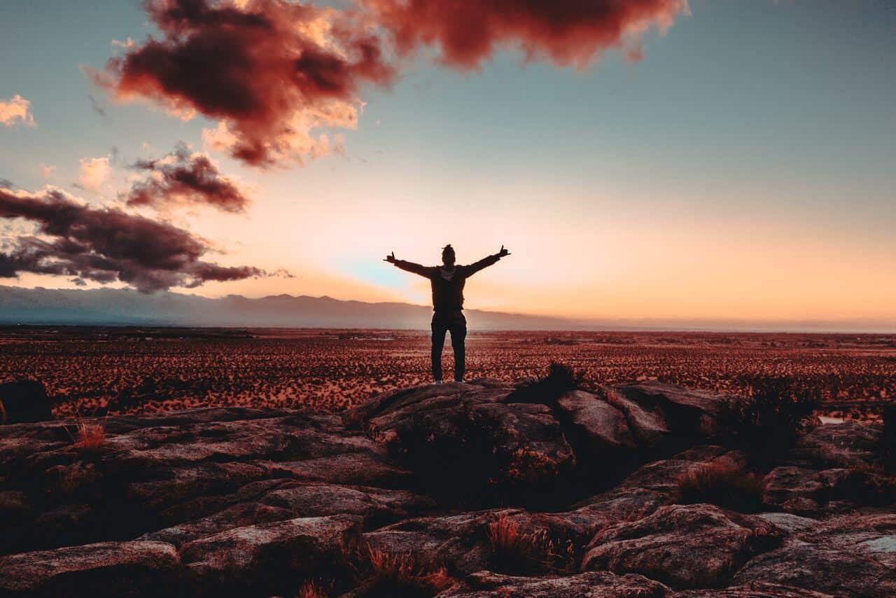 Person standing on a rock with arms raised