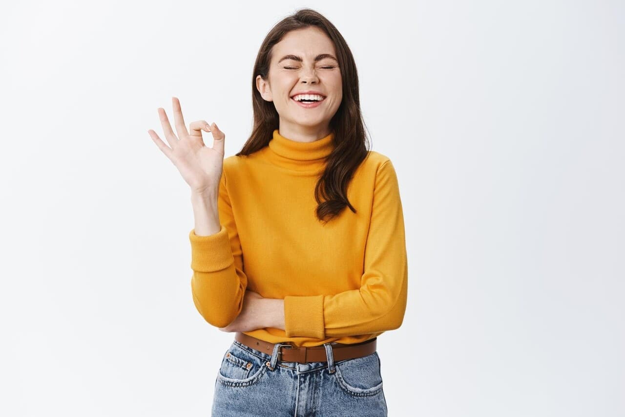 A woman smiling and making an okay gesture