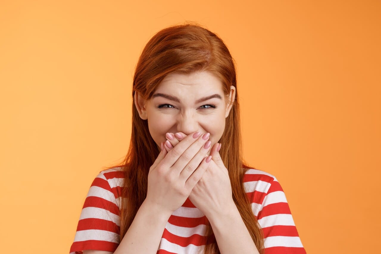 A woman laughing with her hands covering her mouth