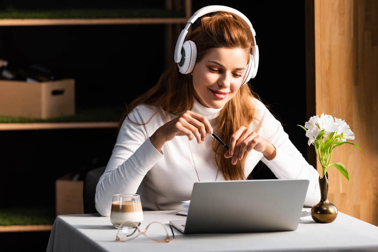 Woman with headphones working on laptop at table