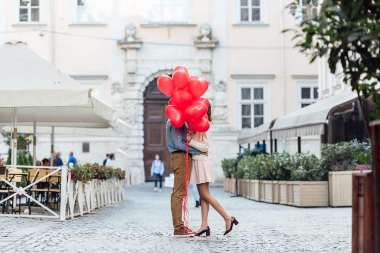 Couple hugging with heart-shaped balloons in the street