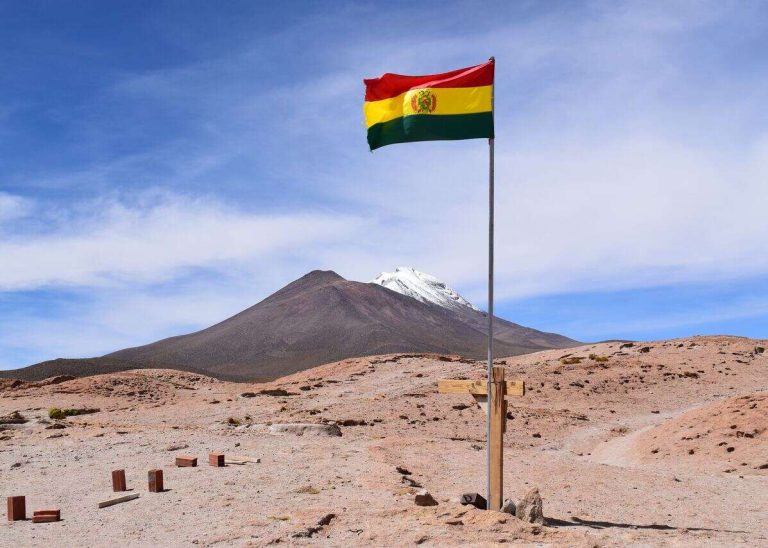 Bolivian flag waving near a snow-capped mountain