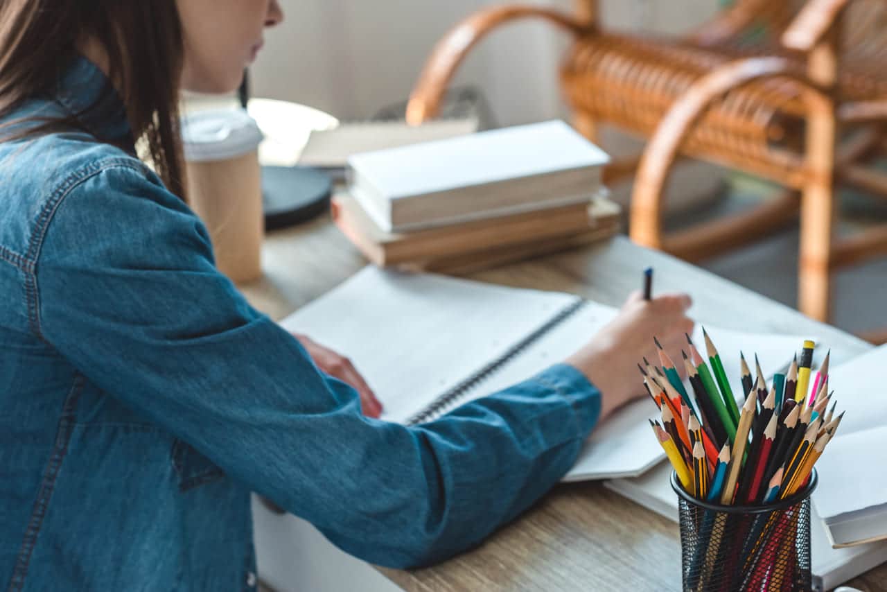 Woman studying at a desk with pencils and notebooks