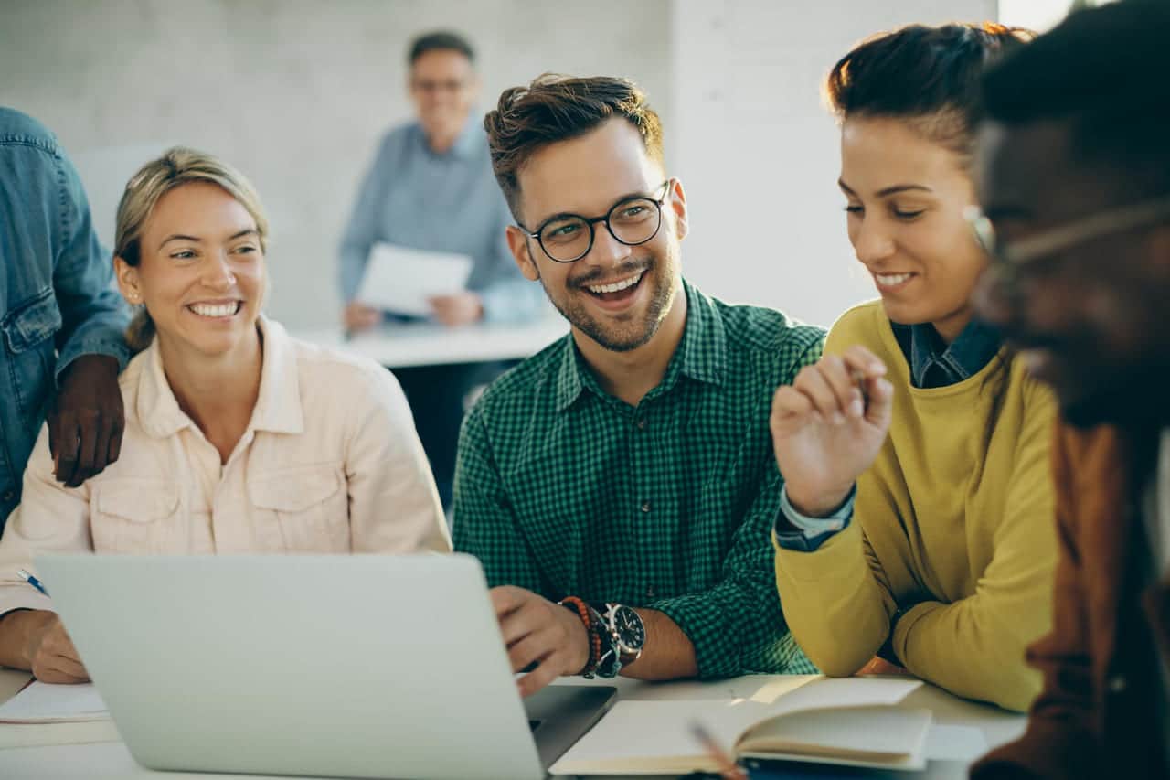 A group of colleagues smiling while working on a laptop