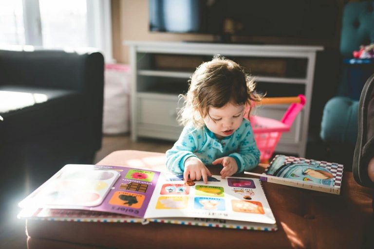 Child reading a colorful picture book indoors.