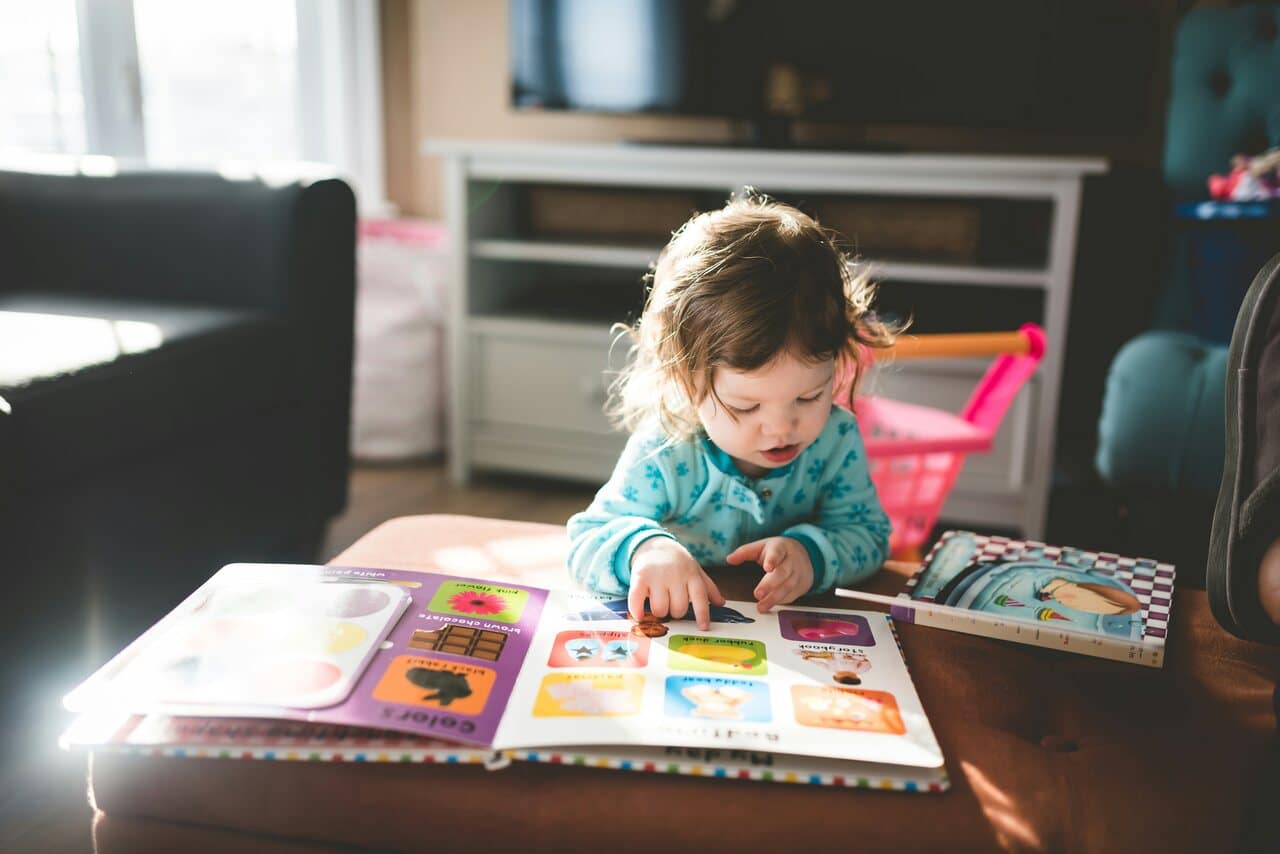 Child reading a colorful picture book indoors.