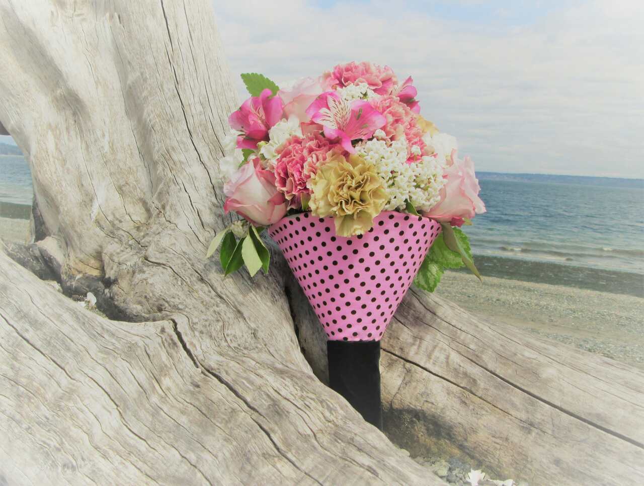 Colorful bouquet leaning against driftwood near the beach