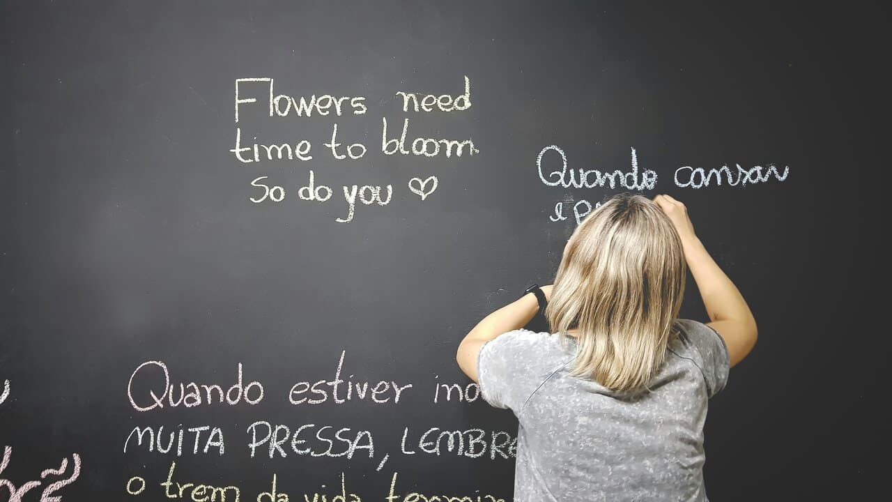 Person writing motivational quotes on a chalkboard.