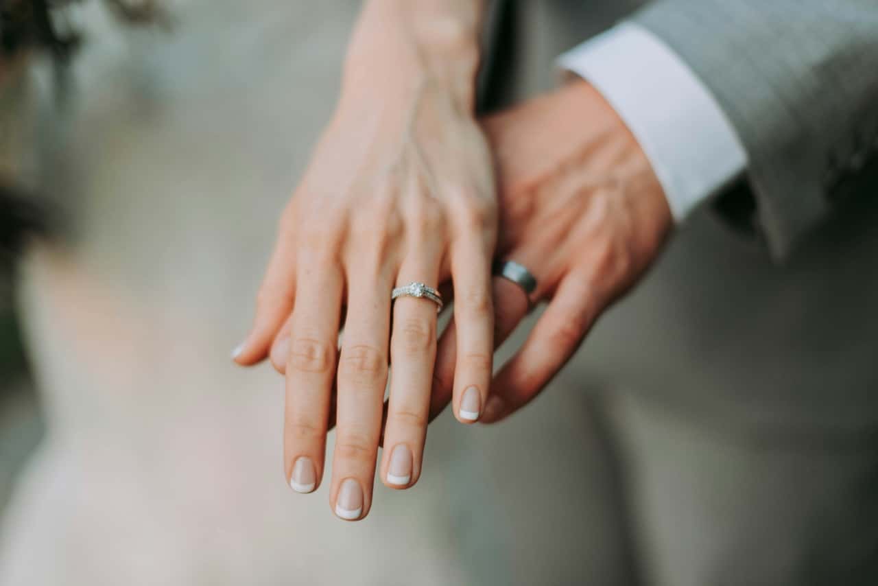 Close-up of bride and groom’s hands with wedding rings, gently resting together after the ceremony