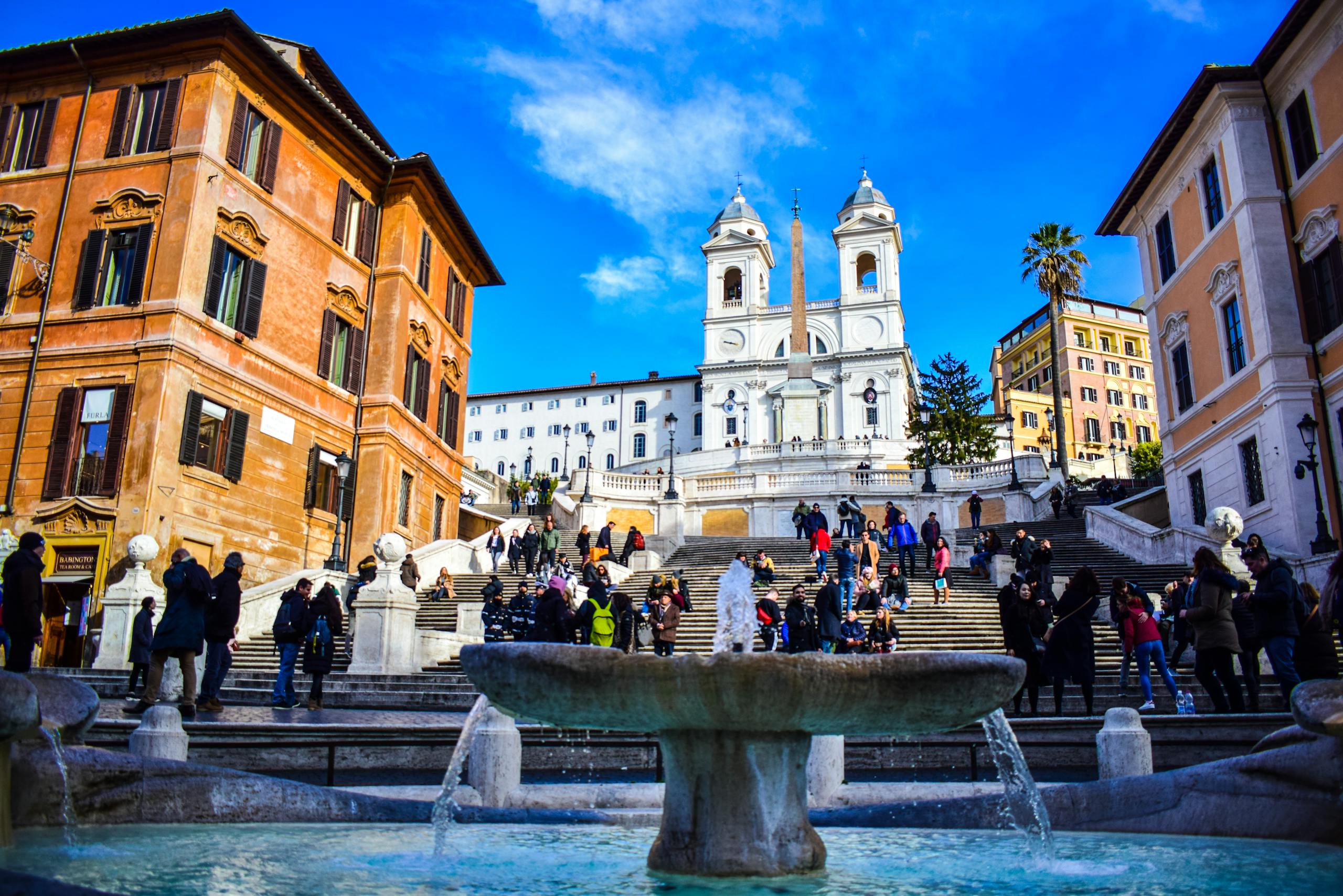 Tourists enjoying a sunny day at the iconic Spanish Steps in Rome, Italy.